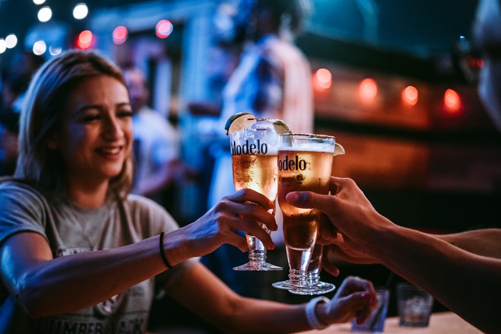 three persons toast their glasses at the bar