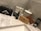 A collection of grooming products is arranged on a marble countertop. Items include a black box with grooming scissors, a tin labeled 'Beard Balm,' a bottle labeled 'Beard Oil,' a wooden brush, and a wooden comb. Decorative ceramic jars with intricate patterns stand in the background.