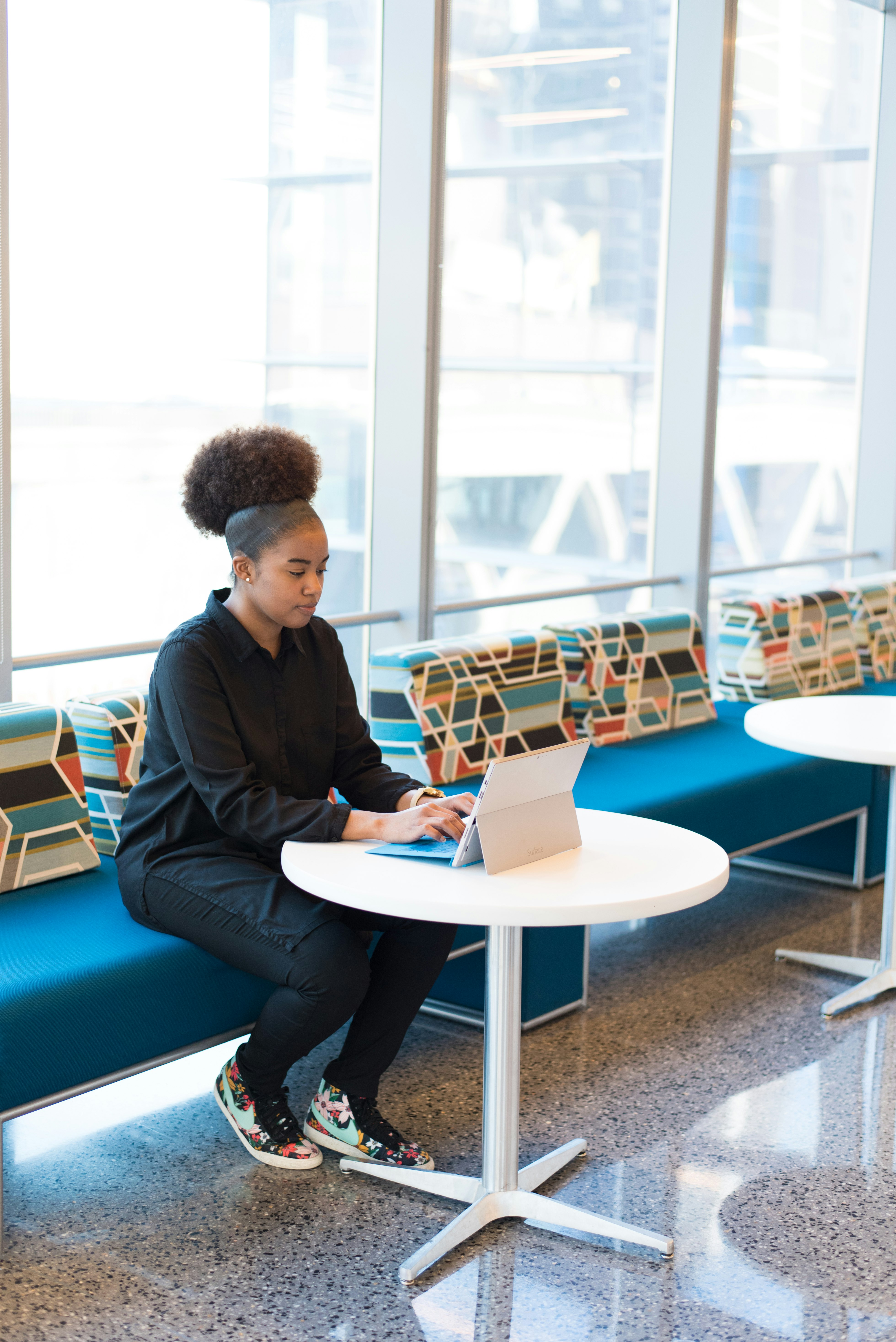 woman sits on sofa while using laptop computer