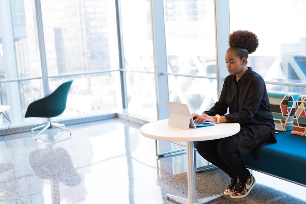 femme s’assoit sur le canapé tout en utilisant une tablette