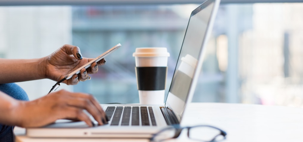 person using smartphone and MacBook