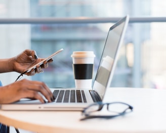 person using smartphone and MacBook