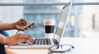 person using smartphone and MacBook