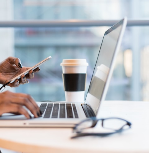 person using smartphone and MacBook