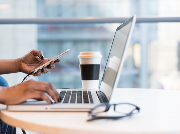 person using smartphone and MacBook