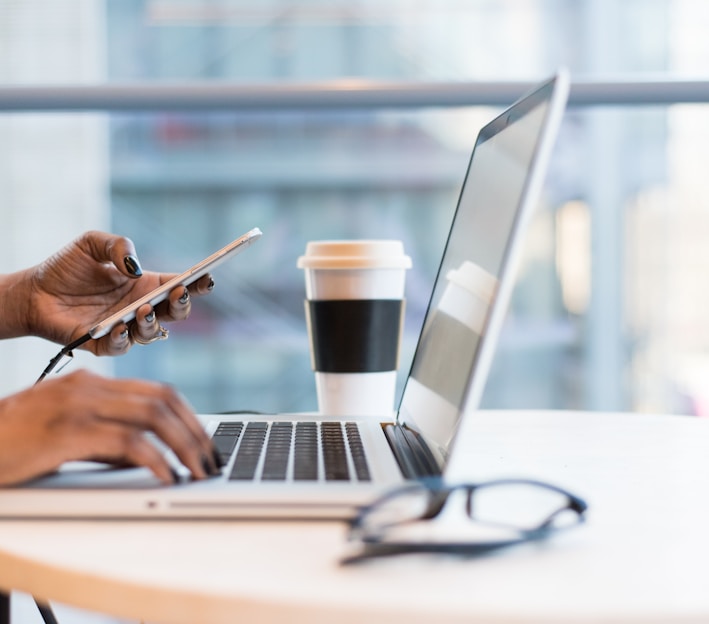 person using smartphone and MacBook