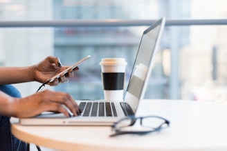 person using smartphone and MacBook for online business