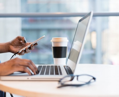 person using smartphone and MacBook