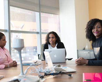 photography of three women sits beside table inside room during daytime