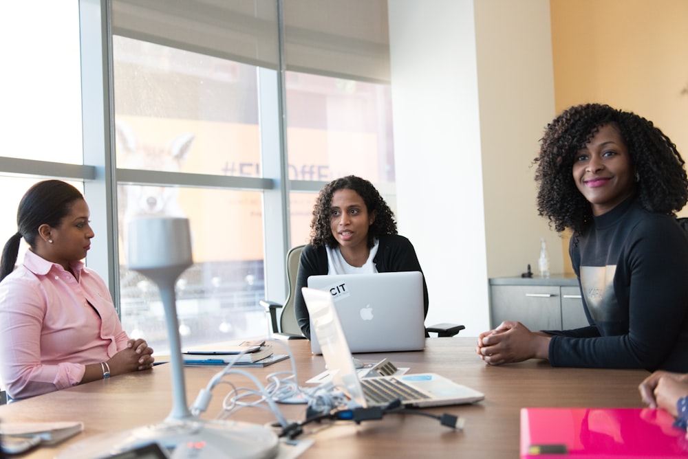 photography of three women sits beside table inside room during daytime