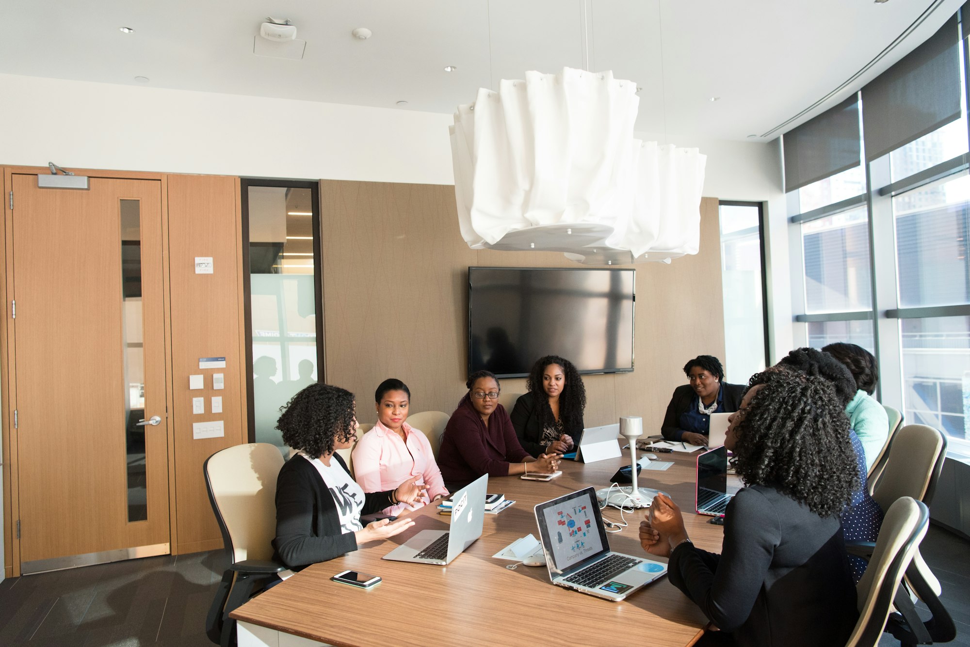 Mesa de reunião com várias mulheres negras debatendo um assunto