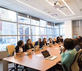 group of people sitting beside rectangular wooden table with laptops