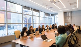 group of people sitting beside rectangular wooden table with laptops