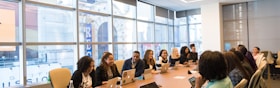 group of people sitting beside rectangular wooden table with laptops