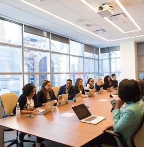 group of people sitting beside rectangular wooden table with laptops