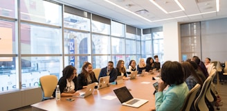 group of people sitting beside rectangular wooden table with laptops