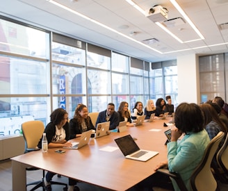 group of people sitting beside rectangular wooden table with laptops