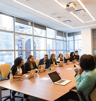 group of people sitting beside rectangular wooden table with laptops