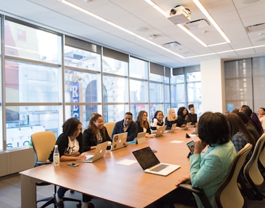 group of people sitting beside rectangular wooden table with laptops