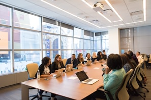 group of people sitting beside rectangular wooden table with laptops