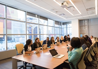 group of people sitting beside rectangular wooden table with laptops