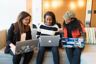 three women sitting on sofa with MacBook