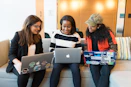 three women sitting on sofa with MacBook
