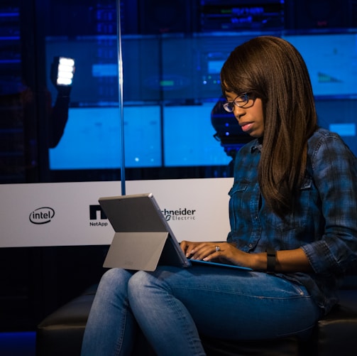 woman in blue and black plaid dress shirt using laptop computer