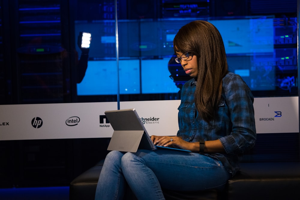 woman in blue and black plaid dress shirt using laptop computer