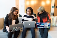 three women sitting on sofa with MacBook