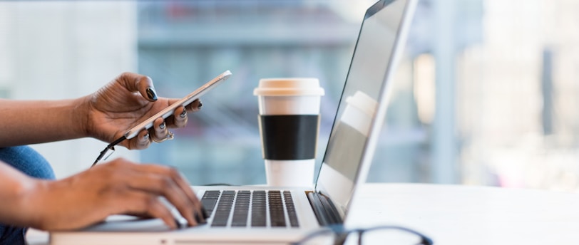 person using smartphone and MacBook