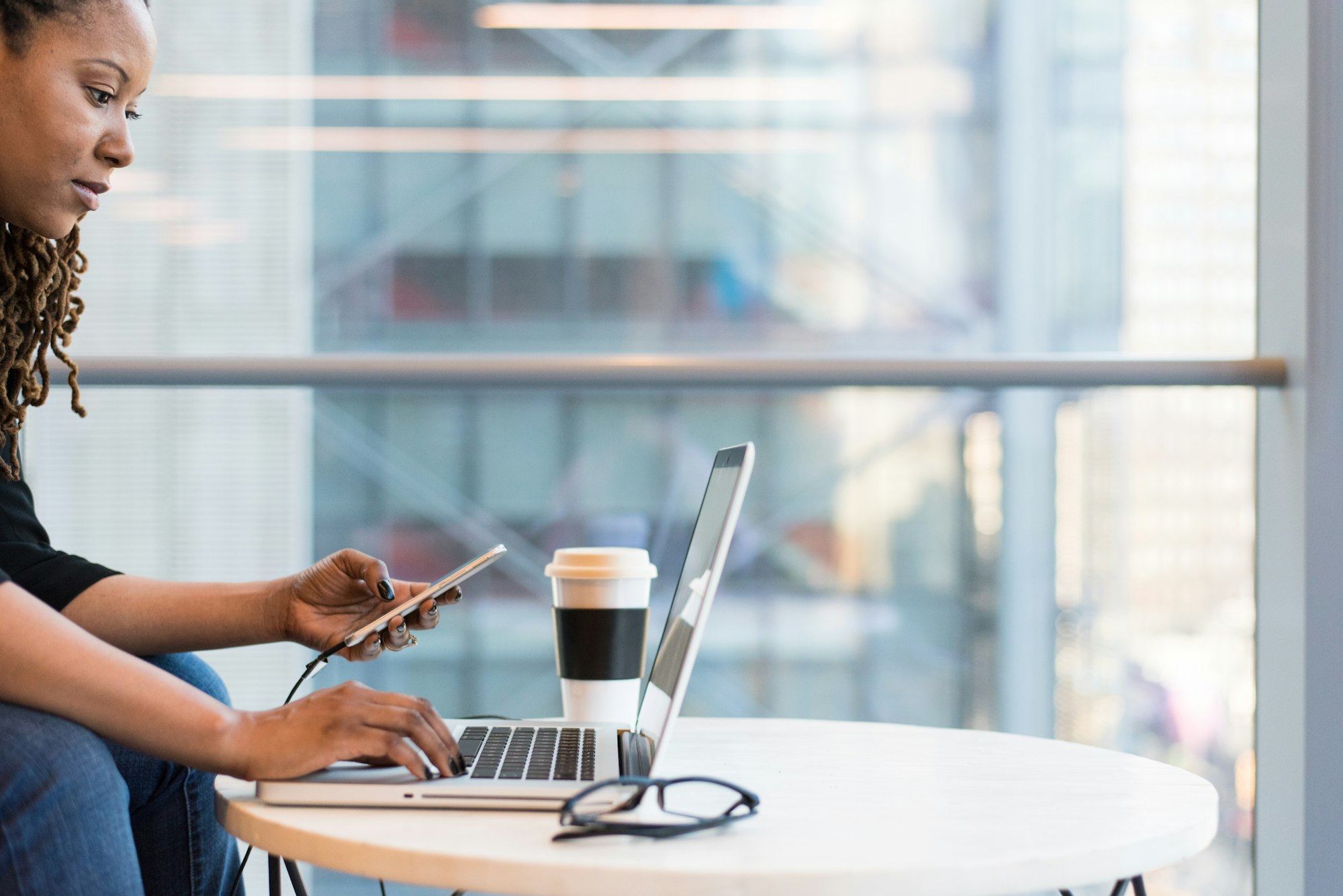 Woman on a computer and phone with cofee.