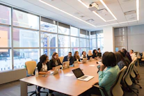 A diverse group of professionals collaborating around a table with laptops and notes.