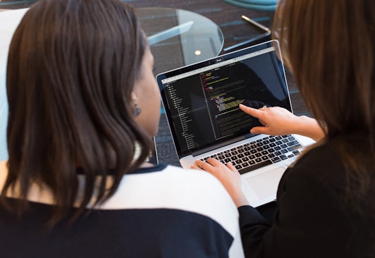 woman using MacBook Pro with person in white top