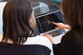 woman using MacBook Pro with person in white top