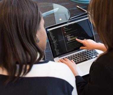 woman using MacBook Pro with person in white top