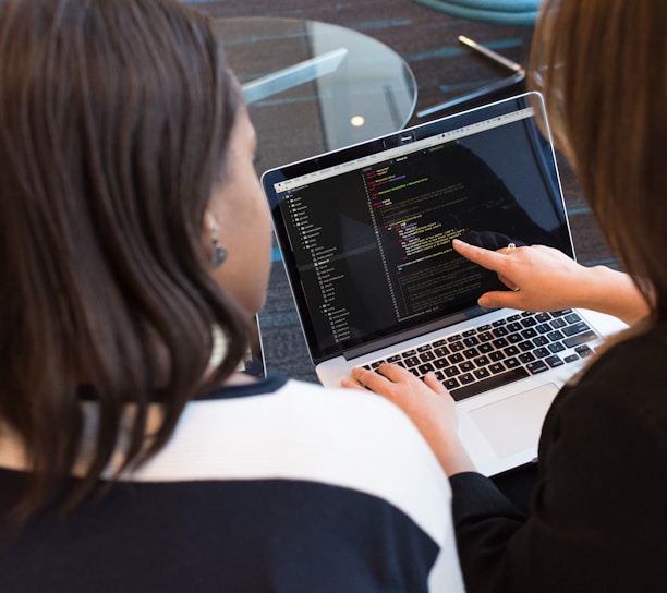 woman using MacBook Pro with person in white top