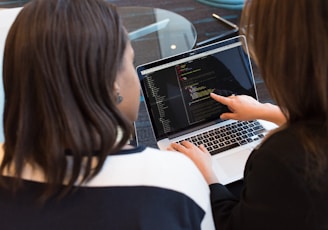 woman using MacBook Pro with person in white top