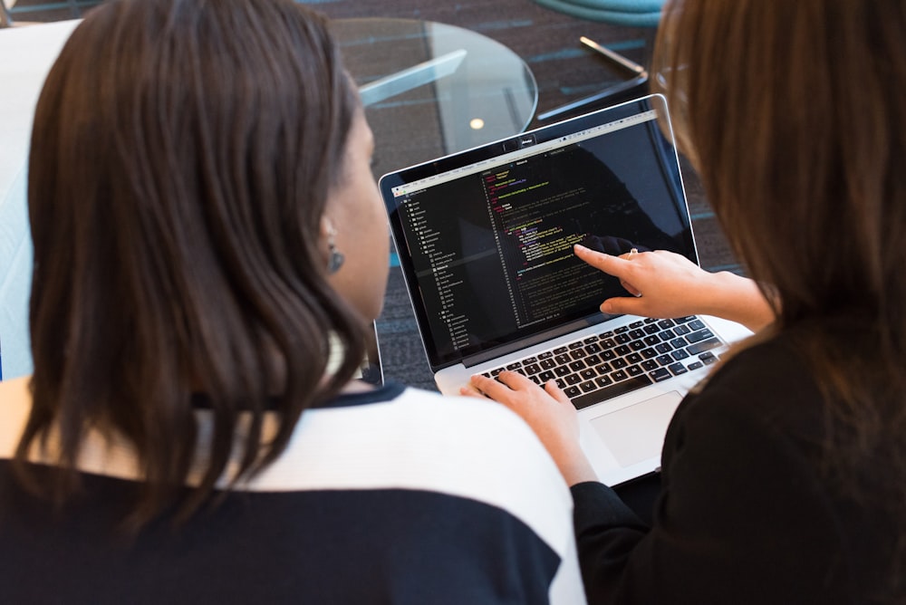 woman using MacBook Pro with person in white top