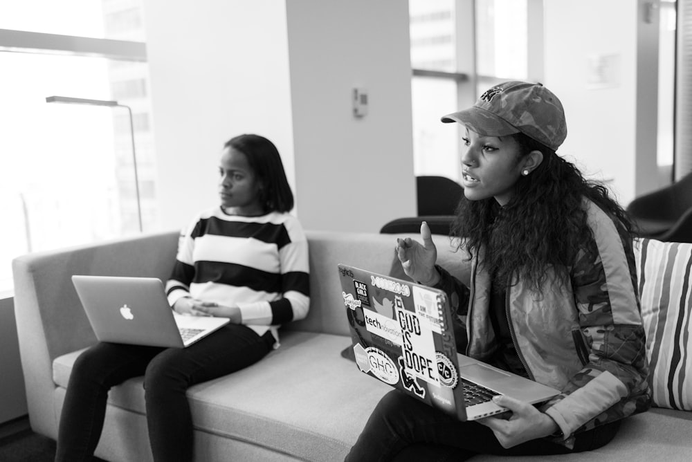 two women holding laptops