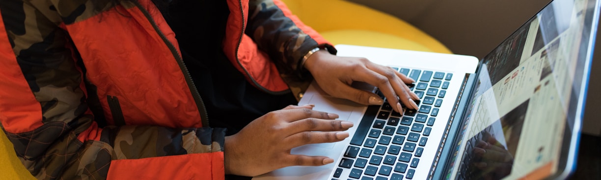 woman in red and black jacket using MacBook Pro