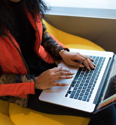 woman in red and black jacket using MacBook Pro