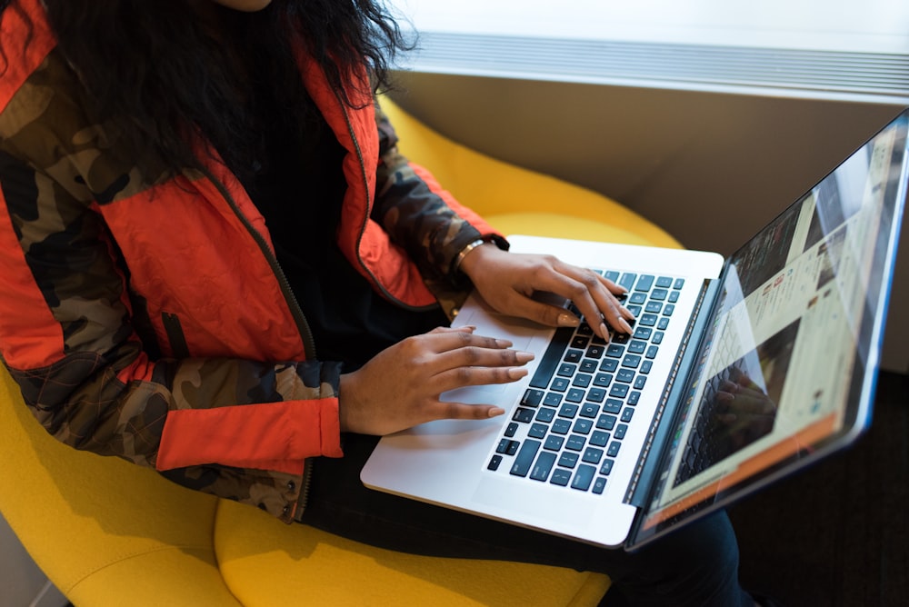 빨간색과 검은색 재킷을 입은 여성이 MacBook Pro를 사용하고 있습니다.