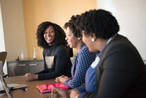 three women sitting beside wooden table