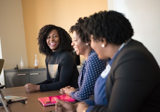 three women sitting beside wooden table