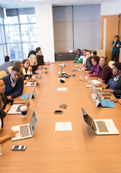 people sitting beside rectangular brown table with laptops