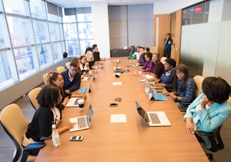 people sitting beside rectangular brown table with laptops