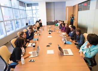 people sitting beside rectangular brown table with laptops