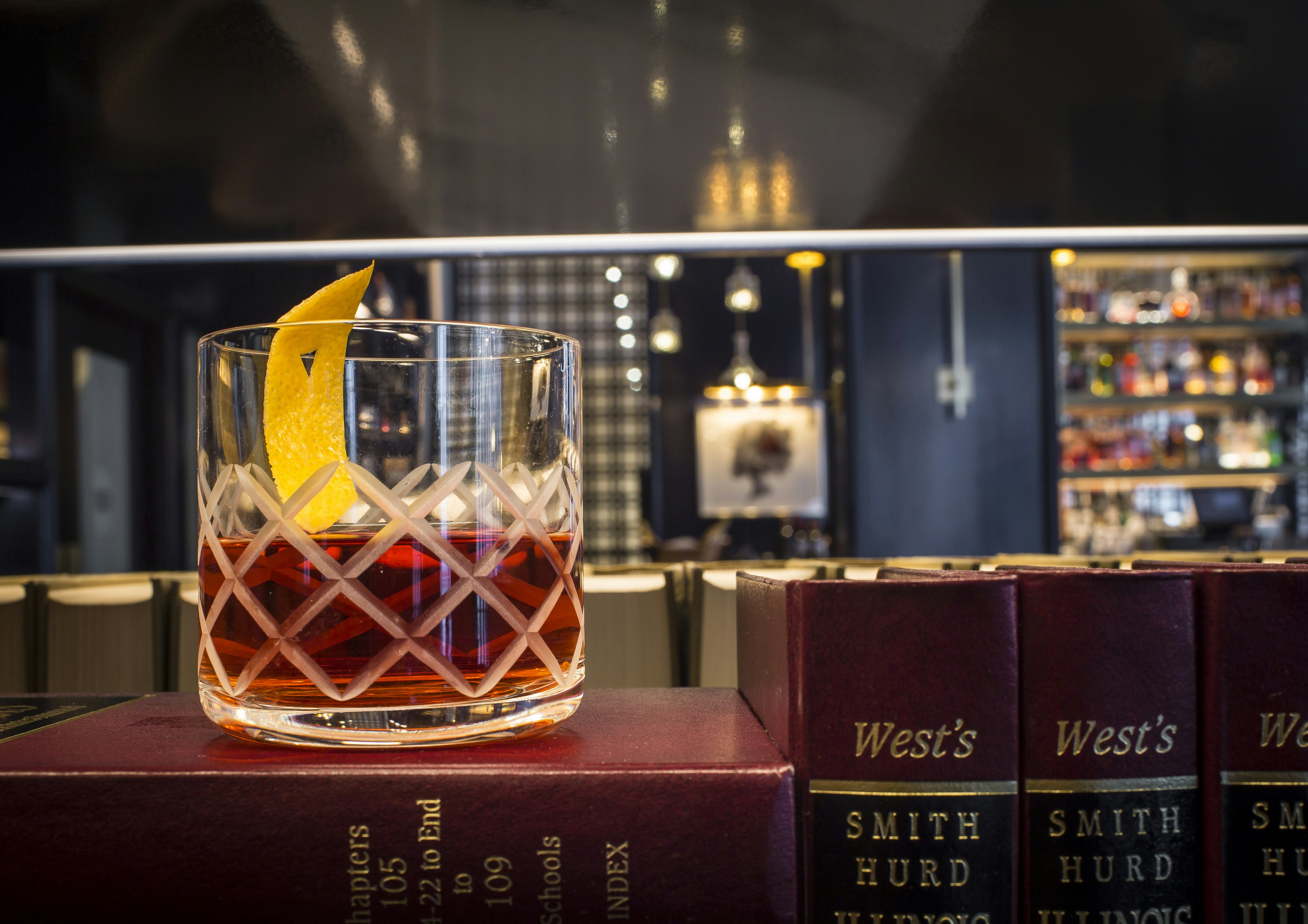Cocktail with citrus peel on a stack of books in a bar