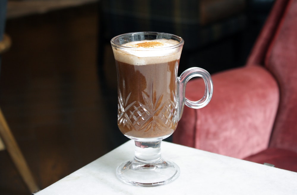 footed clear glass mug on white table